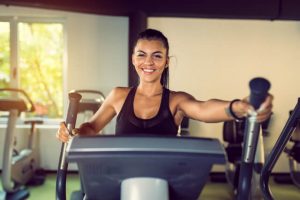 The woman uses a stair climber machine on her regular workout.