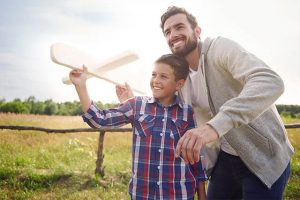 The father teaches her son how to make an aeroplane.